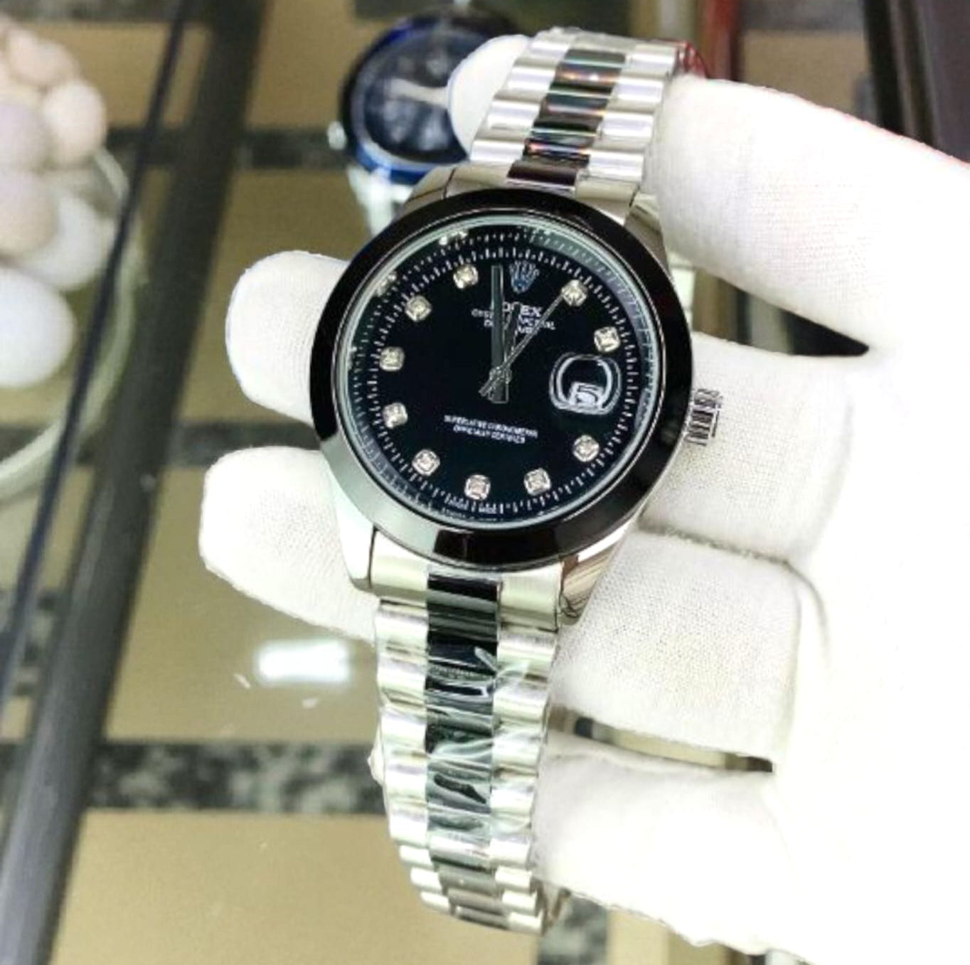Rolex silver back watch with black dial on a white mannequin hand